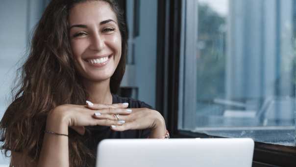 Vrouw lacht naast haar laptop