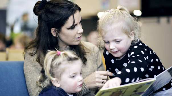 Kinderen lezen boek met docent