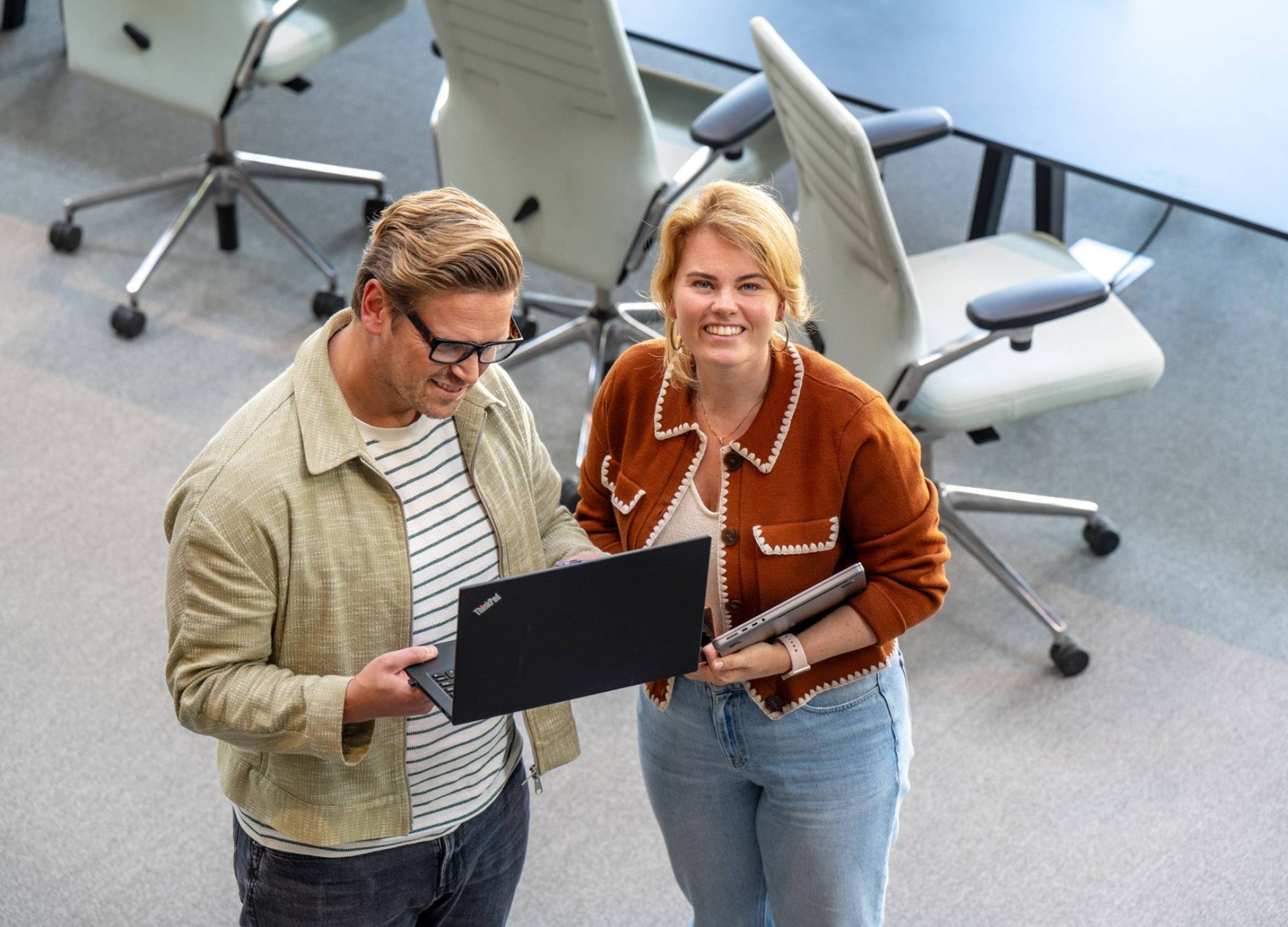 Hbo-masterstudenten bekijken samen informatie op een laptop.