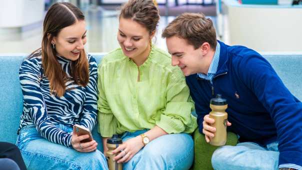 Drie studiekiezers samen op de bank met laptop op schoot