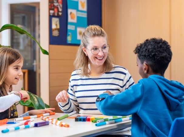 Associate Degree Pedagogisch Educatief Professional met twee leerlingen aan tafel met stiften