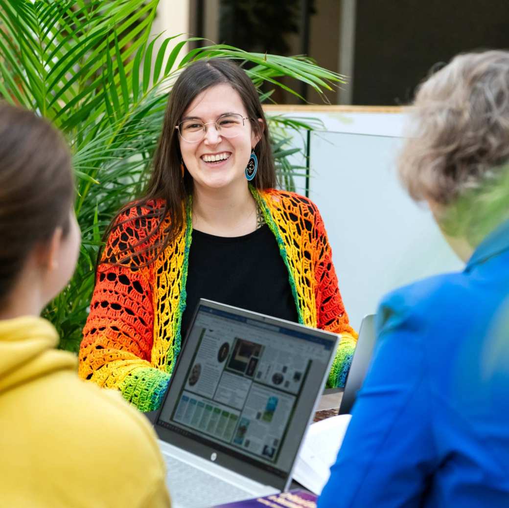 Foto Master Academie Educatie. 3 masterstudenten werken samen aan een tafel met een laptop in het midden op Kapittelweg 35.