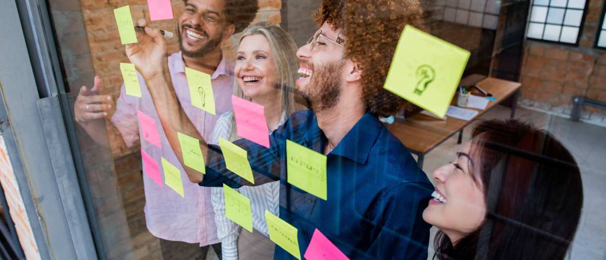 Groep jonge mensen plakken post-its op een glazen wand in een kantoor