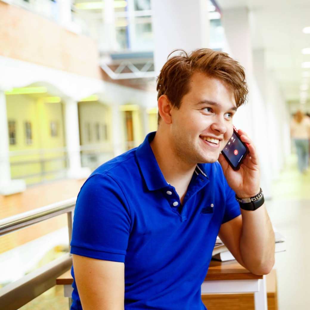 man bellen telefonisch overleg student hal gang