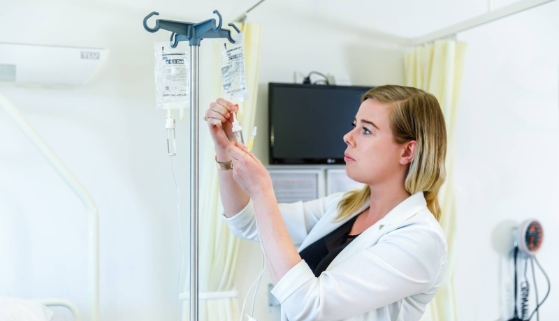 Deeltijdstudent verpleegkunde maakt infuus klaar.