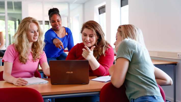 Vier studenten van de eerstegraads lerarenopleiding lachen.