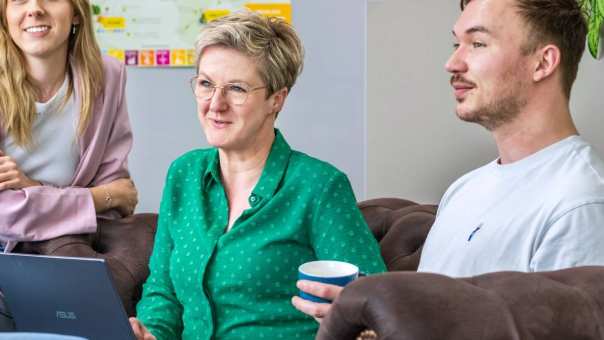 Vier studenten zitten met laptops bij elkaar en luisteren naar elkaar.