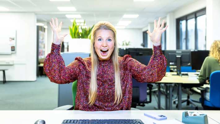 Juichende dame blond achter computer in kantoor