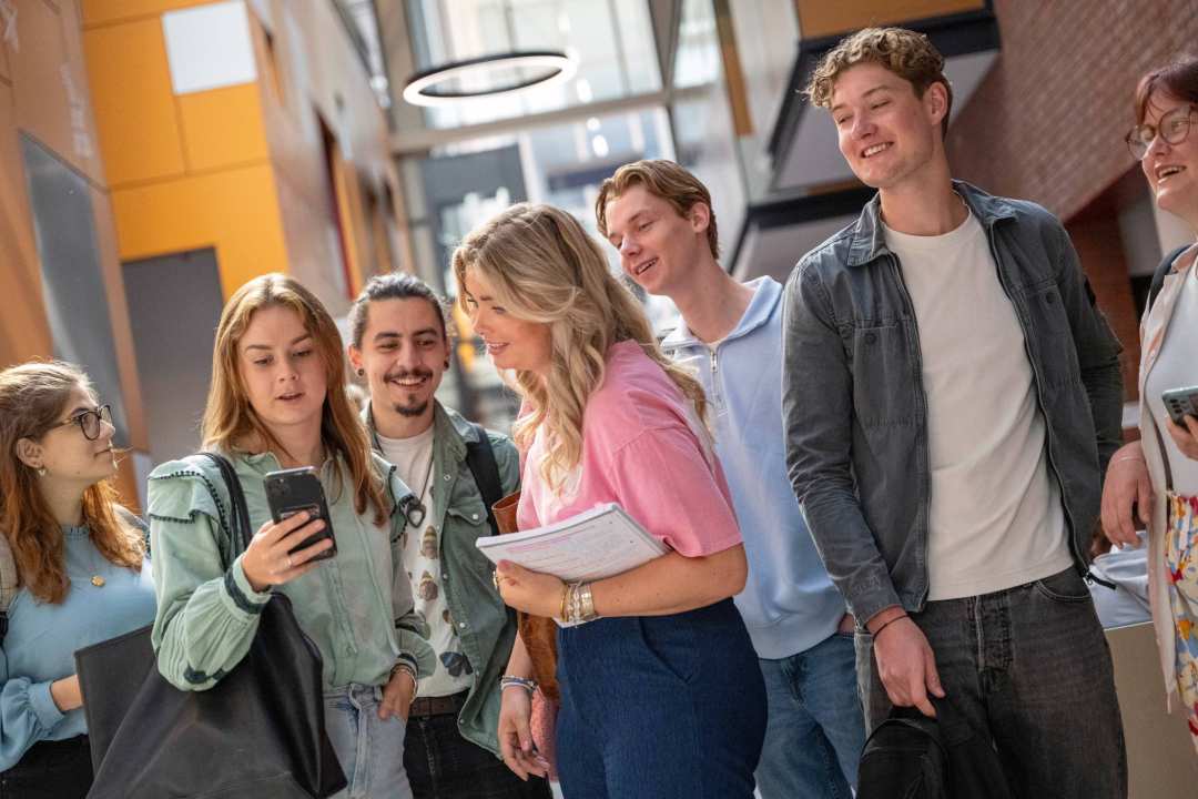 studenten kijken op telefoon inschrijving afronden