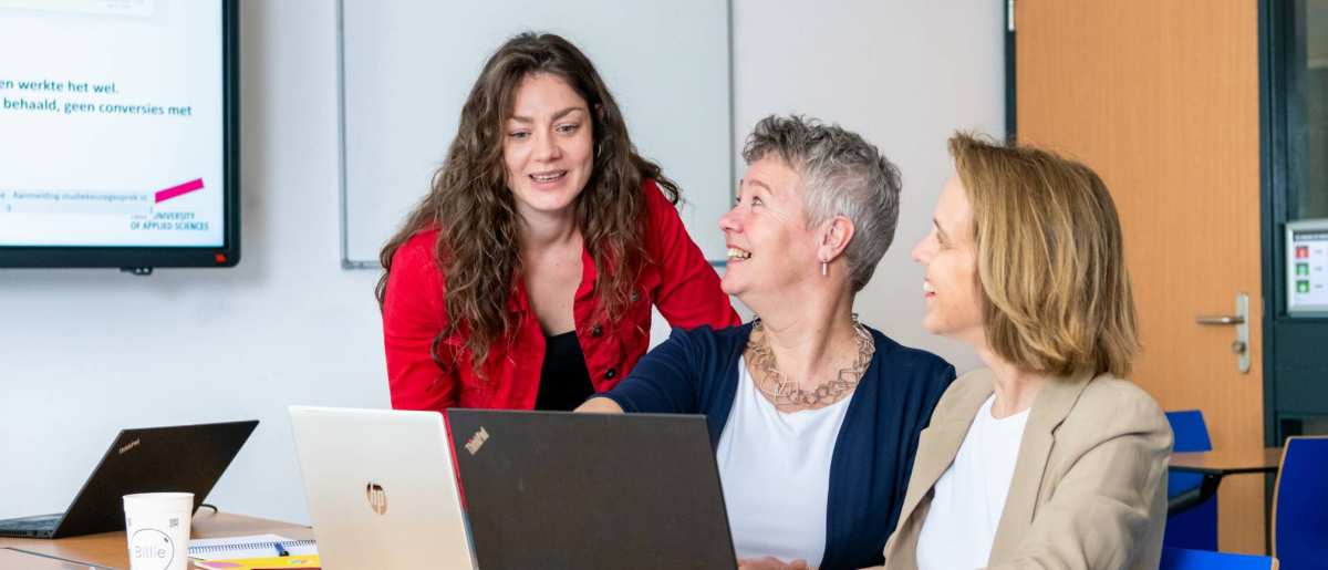 Deelnemers en docenten van de post-hbo Bedrijfskunde in overleg, lachend.