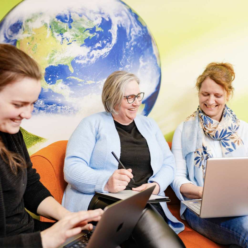 3 duale studenten Praktijkondersteuner Huisartsenzorg (POH) lachen met een laptop op schoot.